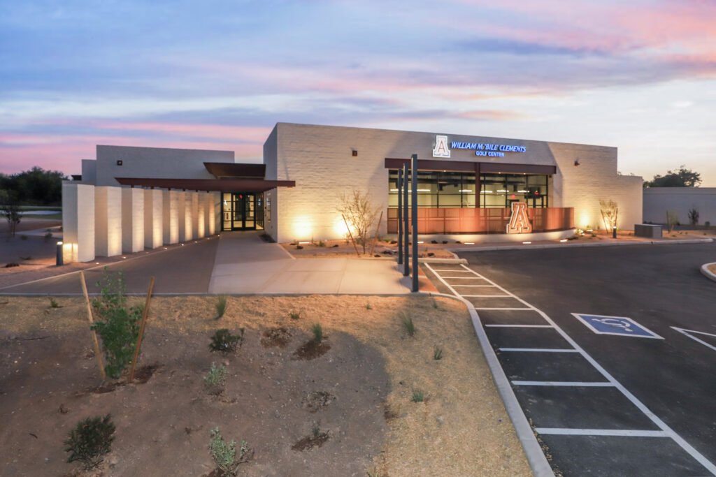 Exterior entryway into lit up clubhouse with sidewalk