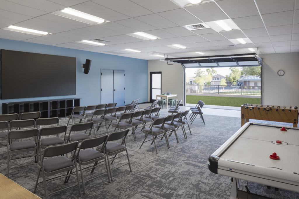 Interior of classroom space with chairs, air hockey table, and open roll up garage door.