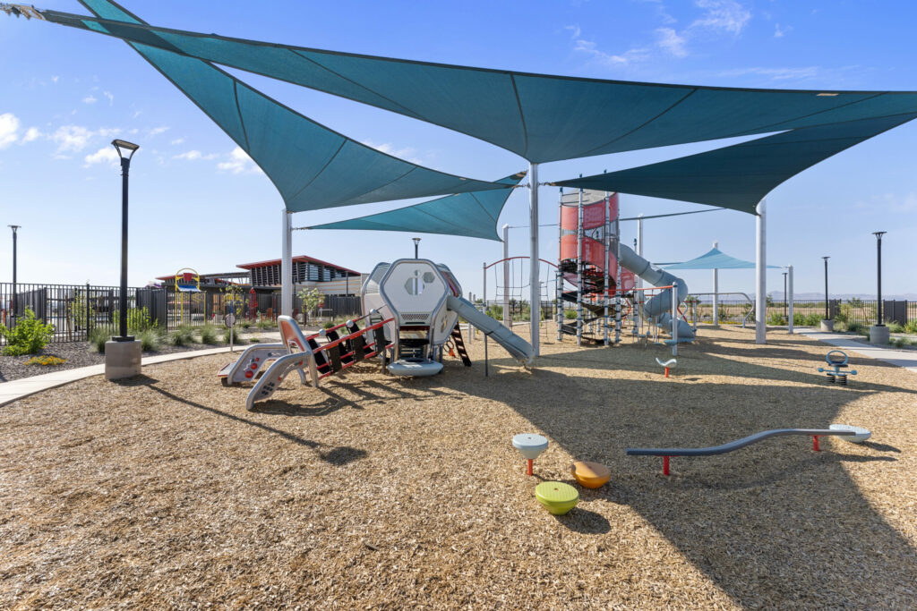 Outdoor play area with teal shade structure and playground equipment