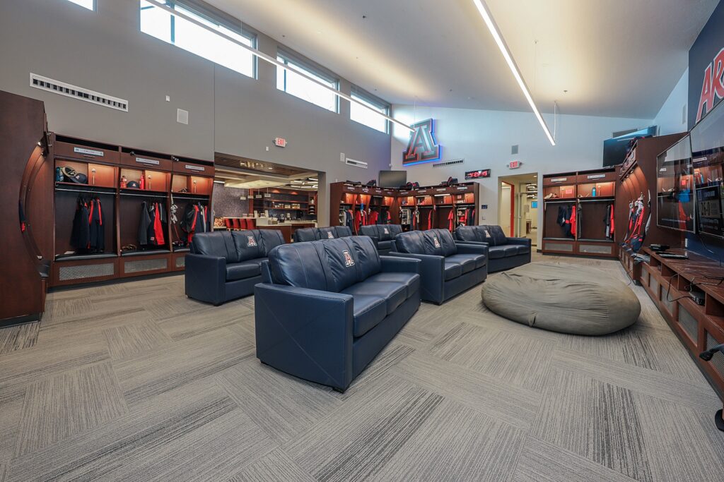 Locker Room with wooden lockers and blue recliner couches facing a screen