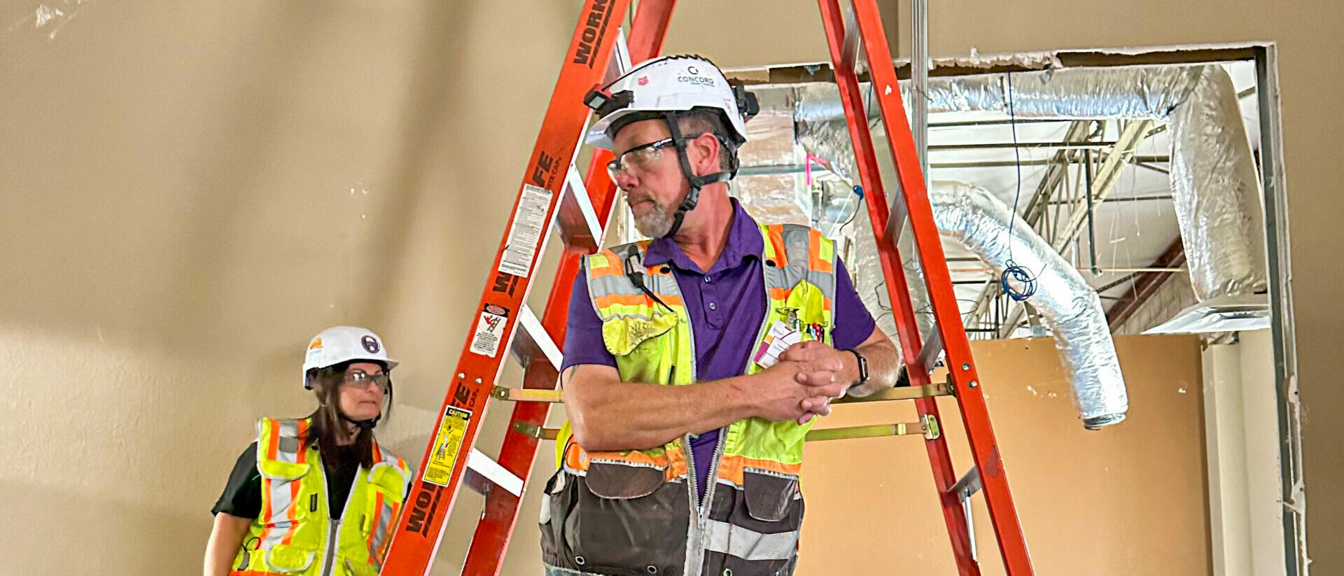 superintendent standing in front of a ladder leaning with his project manager behind him