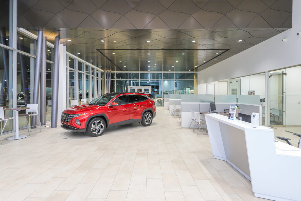 Red car in dealership showroom with white desks