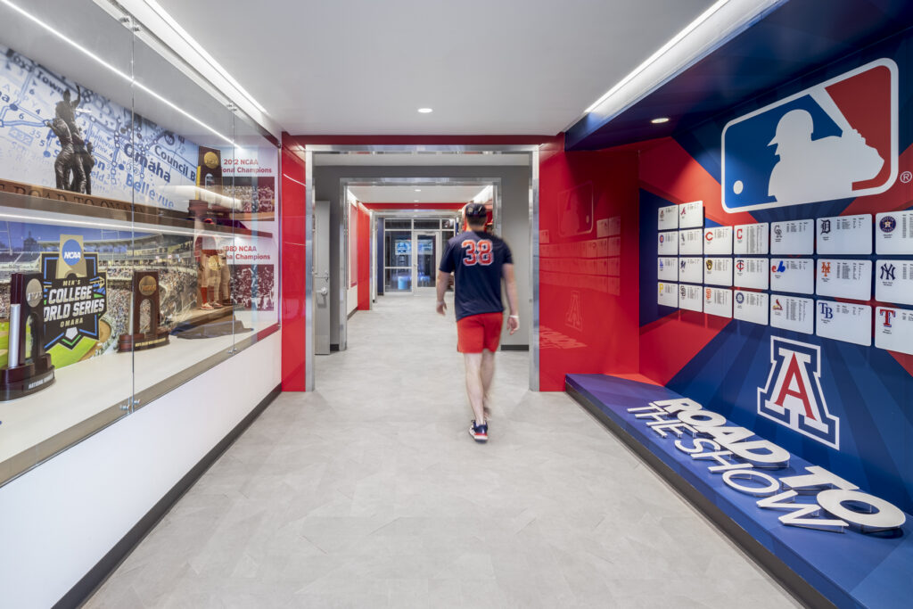 Interior shot of the hallway inside the clubhouse. trophies are displayed on one side of the wall and plaques on the other side with someone walking away